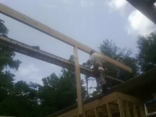 Carpenter setting a ridge beam over a new addition frame — Ice Dam Removal by Roofing Brothers in Valrico