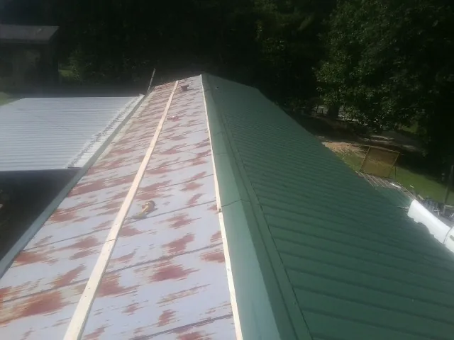 Old rusted panels beside newly installed green metal roofing — Wind Damage Roof Repair by Roofing Brothers in Valrico