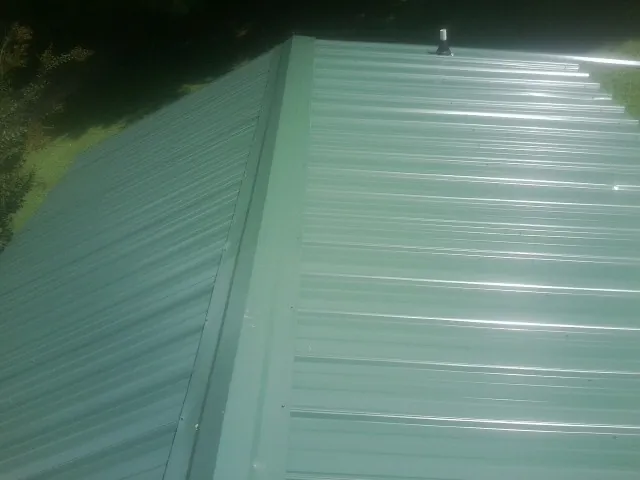 New green metal panels meeting at the ridge of a roof — Flat Roof Repair work by our crew in Valrico