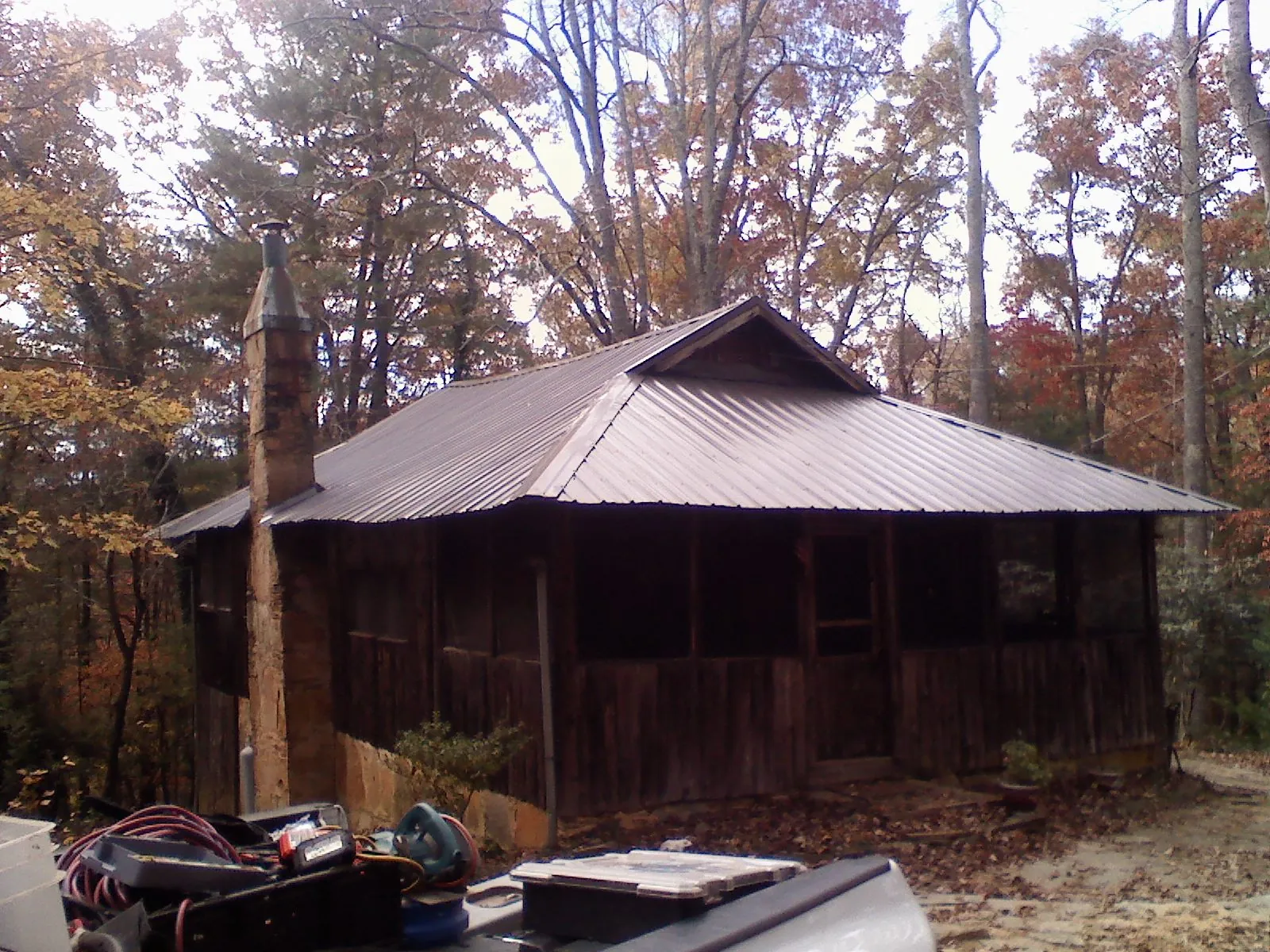 Brown metal hip roof on an old cabin with a stone chimney in Valrico