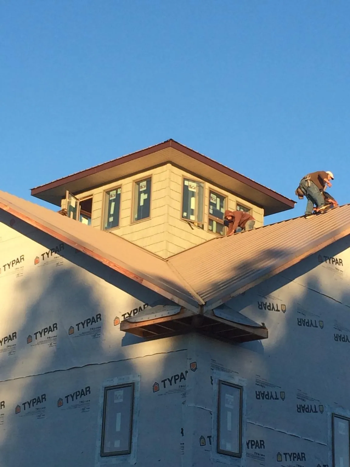 Roofers working around a rooftop cupola on a new metal roof at sunset — Roof Waterproofing in Valrico by Roofing Brothers